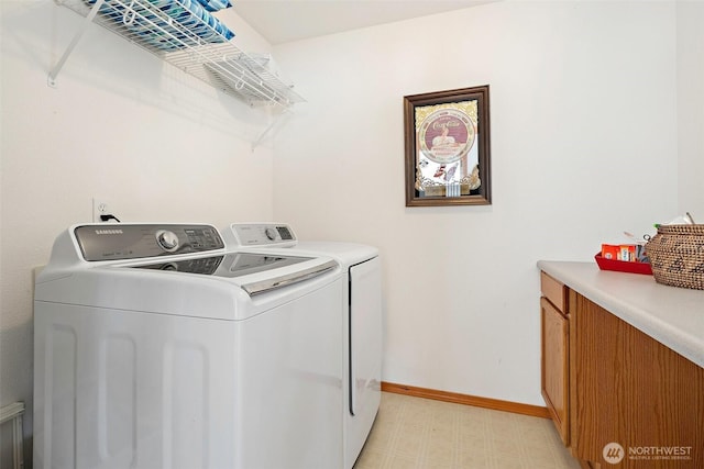 laundry area featuring light floors, baseboards, washer and clothes dryer, and cabinet space