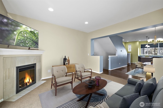 living room featuring a tiled fireplace, a notable chandelier, recessed lighting, and baseboards