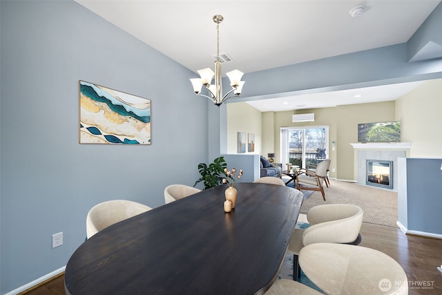 dining room with a tiled fireplace, visible vents, an inviting chandelier, and baseboards