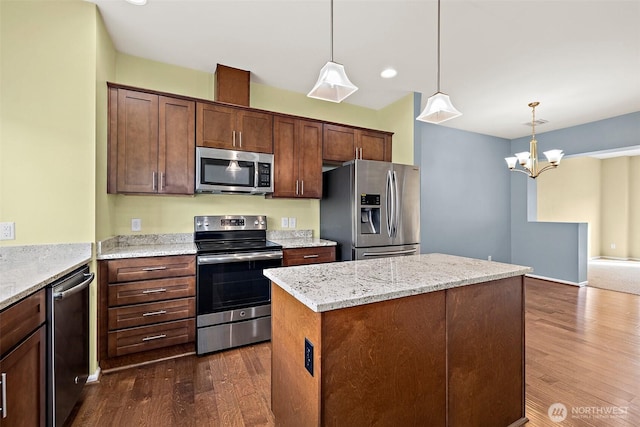 kitchen with decorative light fixtures, a kitchen island, dark wood-style floors, stainless steel appliances, and light stone countertops