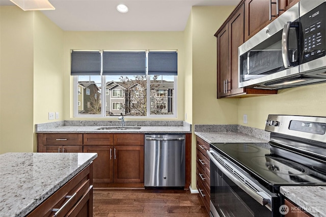 kitchen with a sink, light stone counters, recessed lighting, stainless steel appliances, and dark wood-style flooring