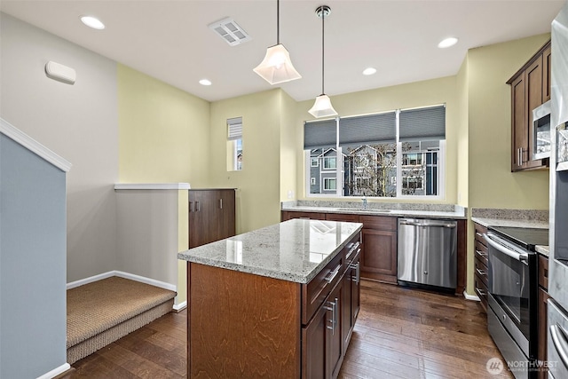 kitchen with visible vents, stainless steel appliances, dark wood-type flooring, and light stone countertops