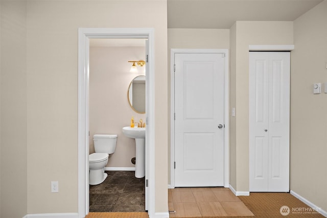 bathroom with baseboards, toilet, and tile patterned flooring