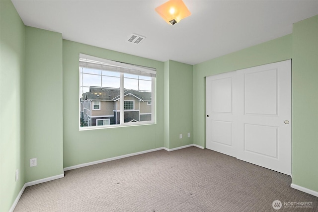 unfurnished bedroom with a closet, visible vents, baseboards, and carpet floors