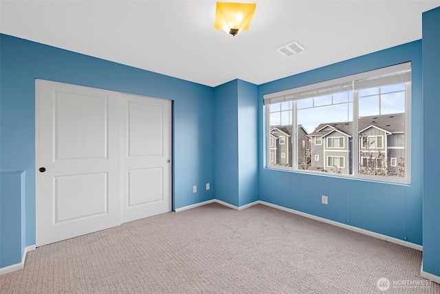 unfurnished bedroom featuring visible vents, carpet floors, baseboards, and a closet