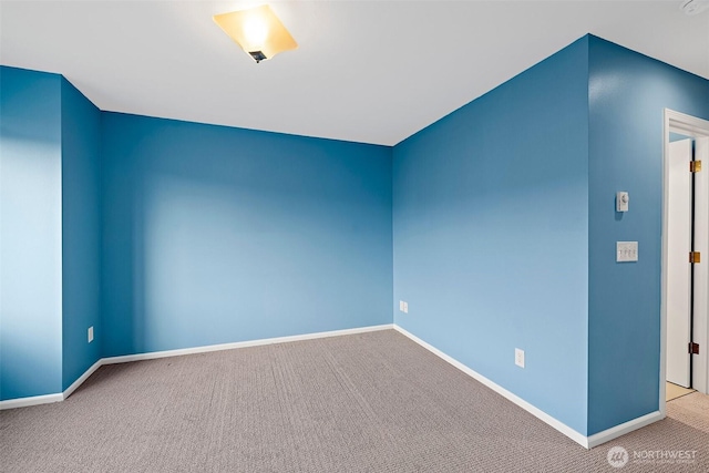 carpeted spare room featuring baseboards