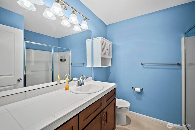 bathroom featuring tile patterned flooring, baseboards, toilet, a stall shower, and vanity