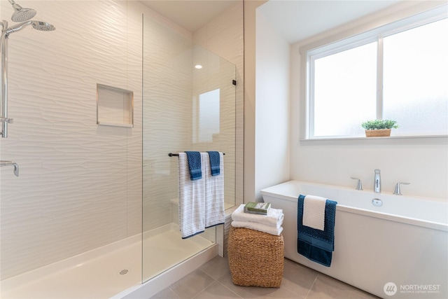 full bathroom featuring tile patterned flooring, a stall shower, and a freestanding tub