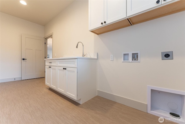 washroom featuring a sink, cabinet space, baseboards, hookup for an electric dryer, and hookup for a washing machine