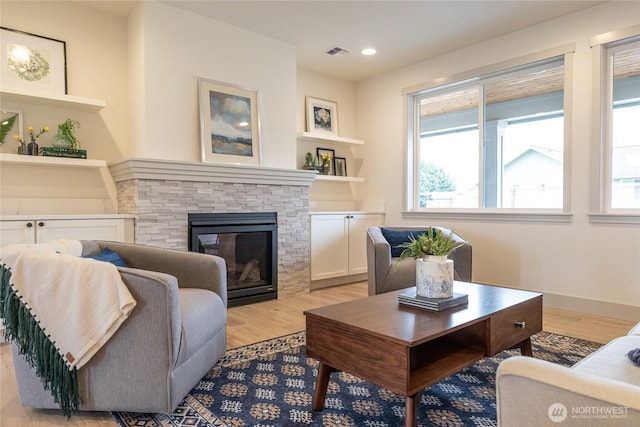 living area with visible vents, recessed lighting, a fireplace, and light wood-type flooring