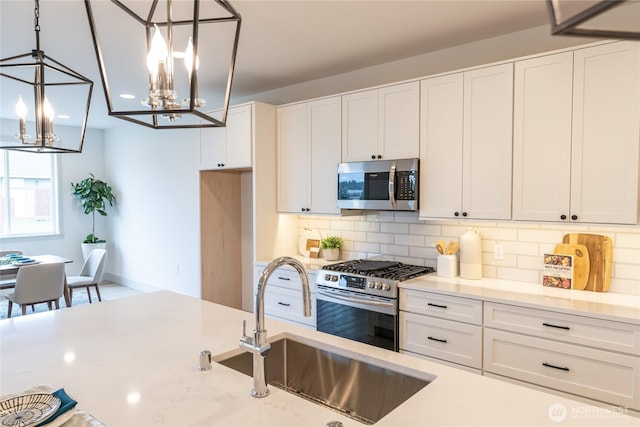 kitchen with decorative backsplash, white cabinets, appliances with stainless steel finishes, and a sink