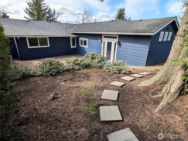 view of front of house with a shingled roof and a patio area