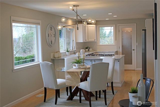dining area with baseboards, a healthy amount of sunlight, and light wood finished floors