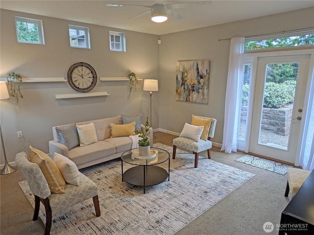 living area with a ceiling fan, baseboards, and carpet floors