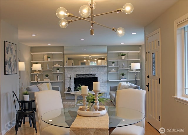dining area with a chandelier, recessed lighting, a fireplace, and wood finished floors