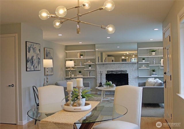 dining area with a notable chandelier, a brick fireplace, recessed lighting, and wood finished floors
