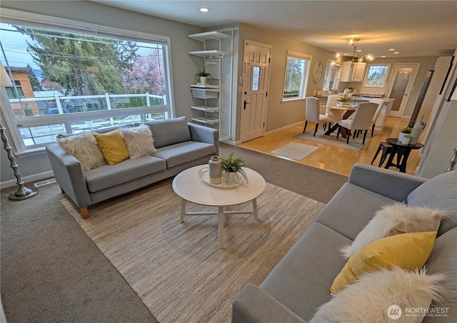 living room with visible vents, baseboards, a notable chandelier, and a healthy amount of sunlight