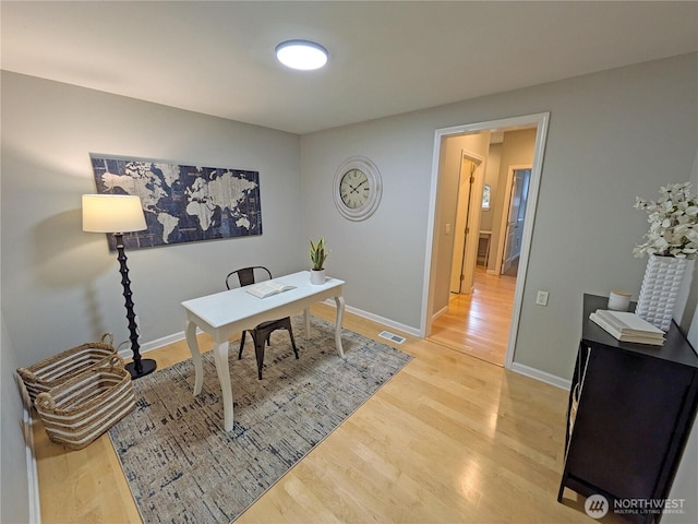 office area featuring visible vents, baseboards, and light wood finished floors