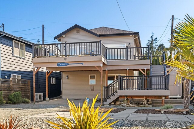 view of front of home with a deck, driveway, fence, a shingled roof, and stairs