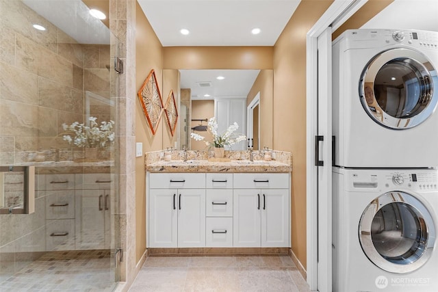 clothes washing area with a sink, stacked washer and clothes dryer, recessed lighting, and laundry area