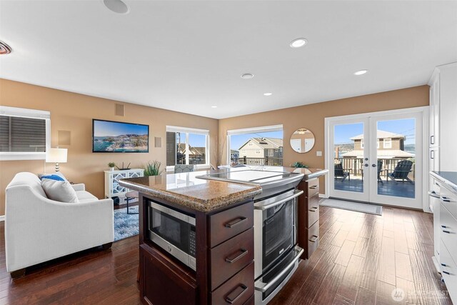 kitchen with dark wood-type flooring, dark brown cabinets, a kitchen island, and stainless steel appliances