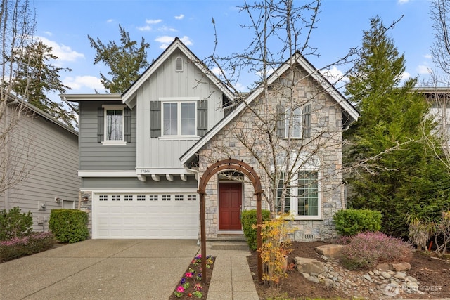 view of front facade with stone siding, board and batten siding, concrete driveway, and an attached garage