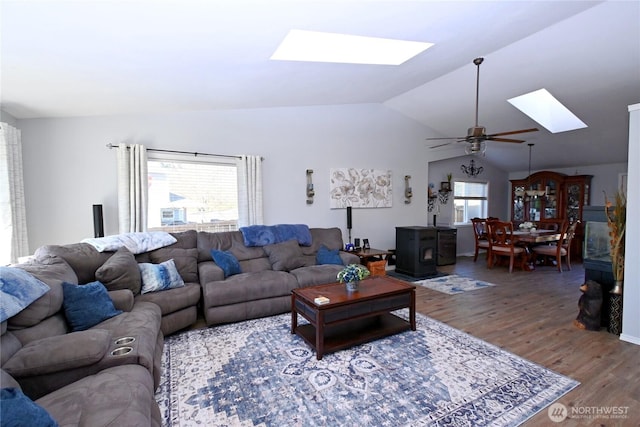 living area featuring a wealth of natural light, vaulted ceiling with skylight, a ceiling fan, and wood finished floors