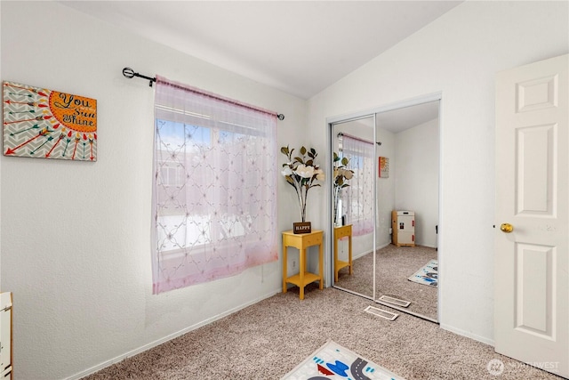 unfurnished bedroom featuring a closet, lofted ceiling, baseboards, and carpet flooring