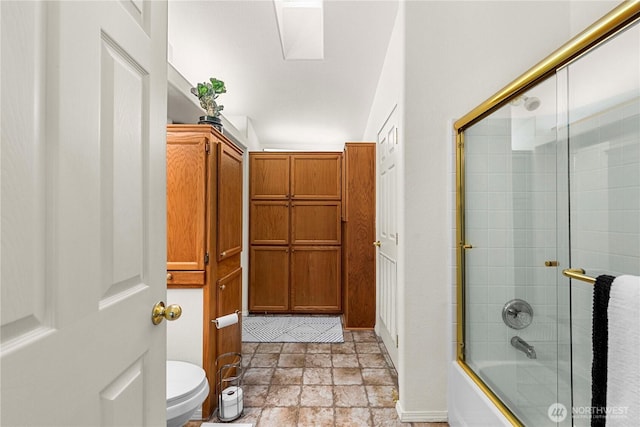 bathroom with combined bath / shower with glass door, stone finish floor, and toilet