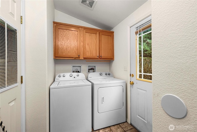 laundry area featuring washer and dryer, visible vents, cabinet space, and a textured wall