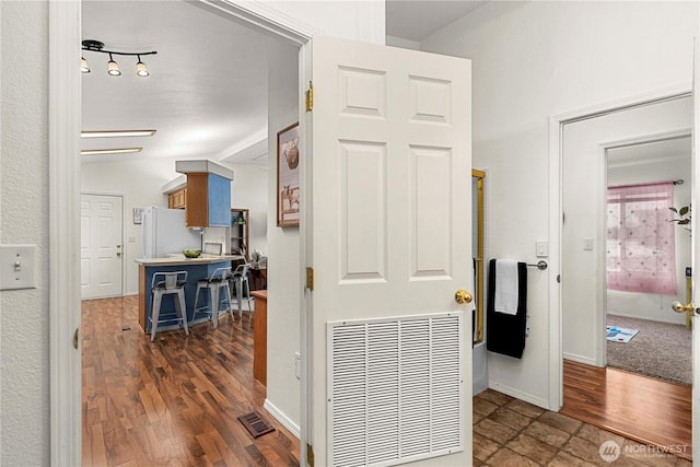 hall featuring visible vents, baseboards, and wood finished floors