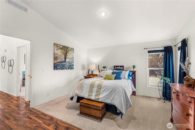 bedroom with vaulted ceiling, wood finished floors, and visible vents