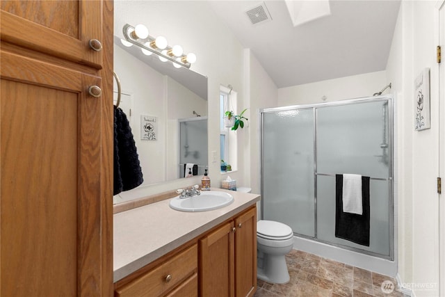 full bathroom with visible vents, a shower stall, stone finish flooring, toilet, and vanity