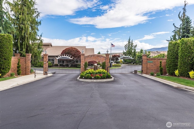 view of road featuring a gate, curbs, sidewalks, and a gated entry