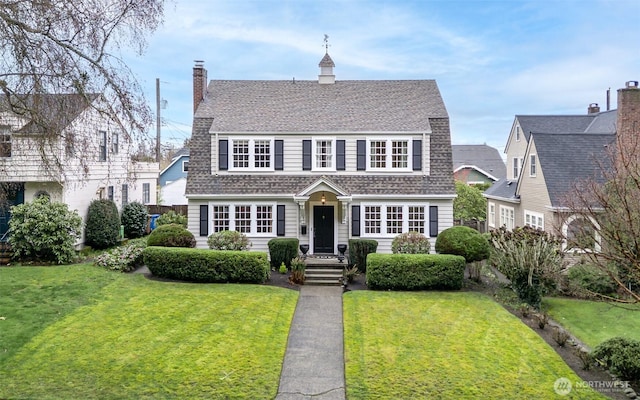 view of front of house featuring a front lawn and a shingled roof