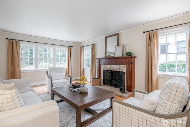 living room featuring a tiled fireplace, light wood-style flooring, and baseboards