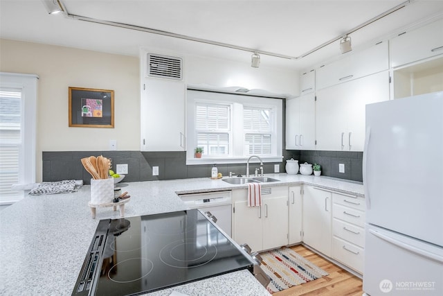 kitchen with visible vents, decorative backsplash, white appliances, white cabinetry, and a sink