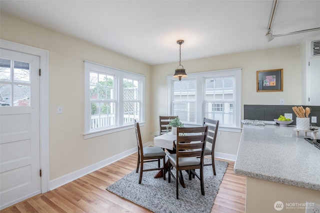 dining room with rail lighting, baseboards, and light wood-type flooring