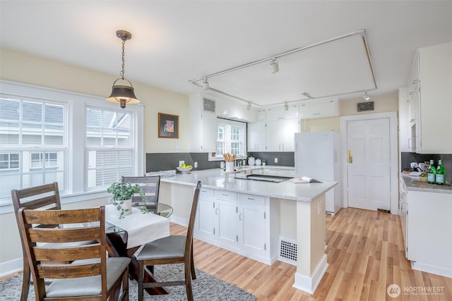 kitchen featuring light wood-style flooring, white cabinets, a peninsula, and freestanding refrigerator