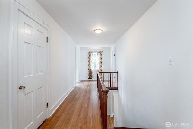 hall featuring an upstairs landing, light wood-style flooring, and baseboards