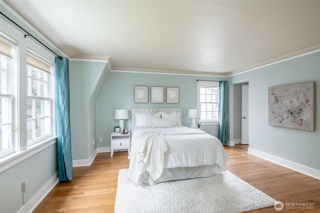 bedroom featuring light wood finished floors, crown molding, and baseboards