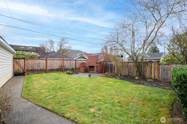 view of yard with a patio, a fenced backyard, and an outdoor brick fireplace