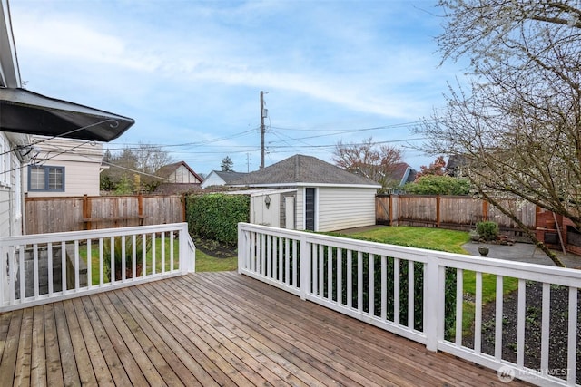 deck featuring a fenced backyard, a lawn, and an outdoor structure