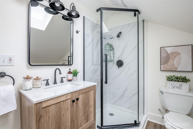 full bath featuring a marble finish shower, vaulted ceiling with skylight, toilet, and vanity