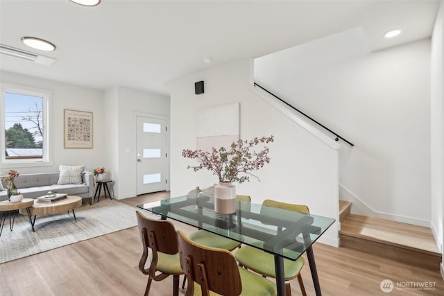 dining room featuring visible vents, baseboards, light wood-style floors, and stairs