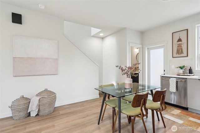 dining room featuring a skylight, baseboards, light wood-style flooring, and recessed lighting