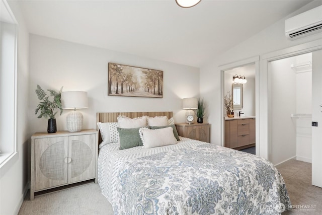 carpeted bedroom with baseboards, lofted ceiling, an AC wall unit, and ensuite bathroom