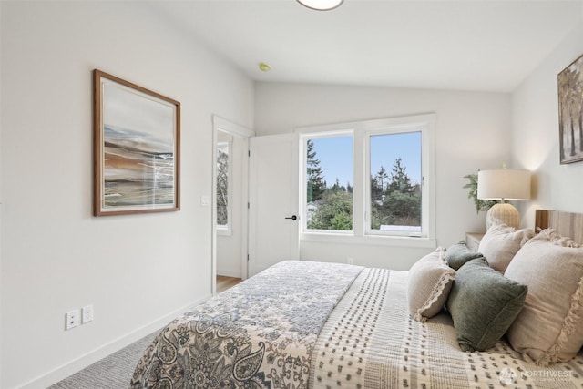 carpeted bedroom featuring baseboards and lofted ceiling