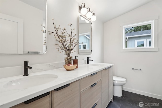 bathroom with a sink, baseboards, toilet, and double vanity