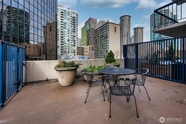 view of patio featuring a view of city, outdoor dining area, and a balcony